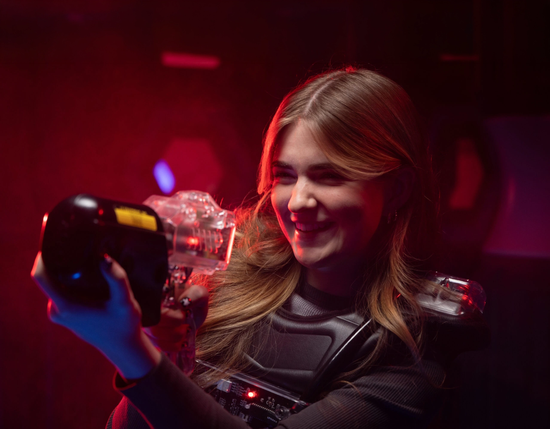Player smiling with a laser tag phaser in the neon arena